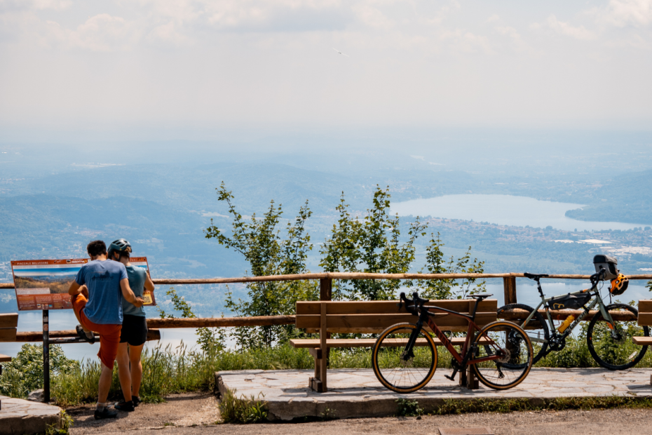 Vista del Belvedere di Varese. Due bici sono appoggiate alle panchine e due ciclisti fotografano il paesaggio.