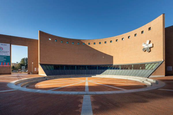 Facciata moderna del MAGA di Gallarate, con una piazza circolare in primo piano e un cielo sereno sullo sfondo.